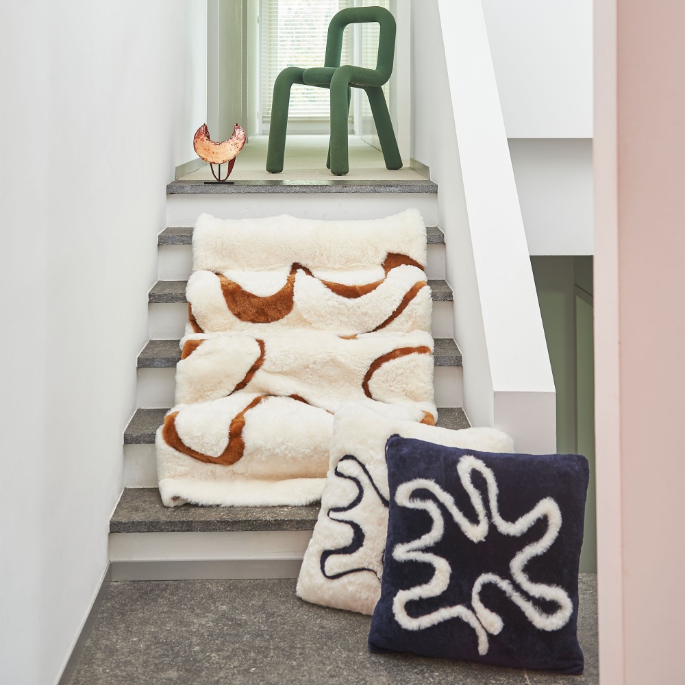 Blue and white sheepskin luxury square cushion  matched with a throw from the same collection and a green mustache chair