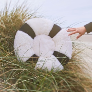 A cushion like a lifebuoy, blue and white. A cushion in natural shearling and sheepskin.