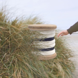 A stool in white and navy-blue sheepskin, oak or birch wood. Seat height 48 cm. Design norki