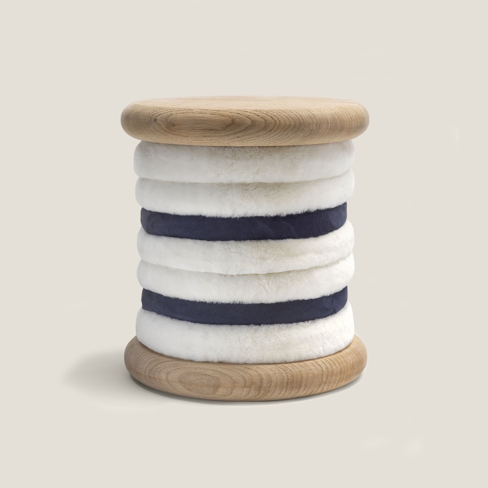 A stool in white and navy-blue sheepskin, oak or birch wood. Seat height 48 cm. Design norki