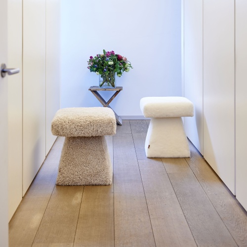 Petits poufs design beige et blanc décorant un dressing luxueux et contemporain