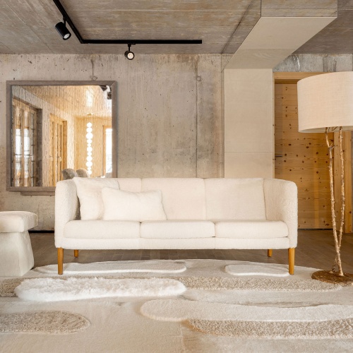 Vintage Hans Wegner sofa, cowhide and sheepskin rug and designer white pouf in the Norki store in Gstaad