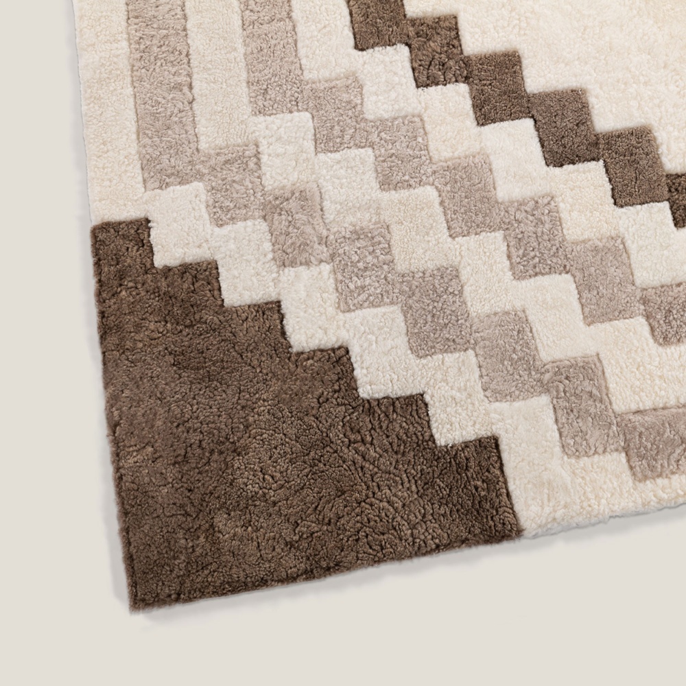 Motif géométrique couleur blanc, beige et marron et finitions soignées pour ce tapis doublé