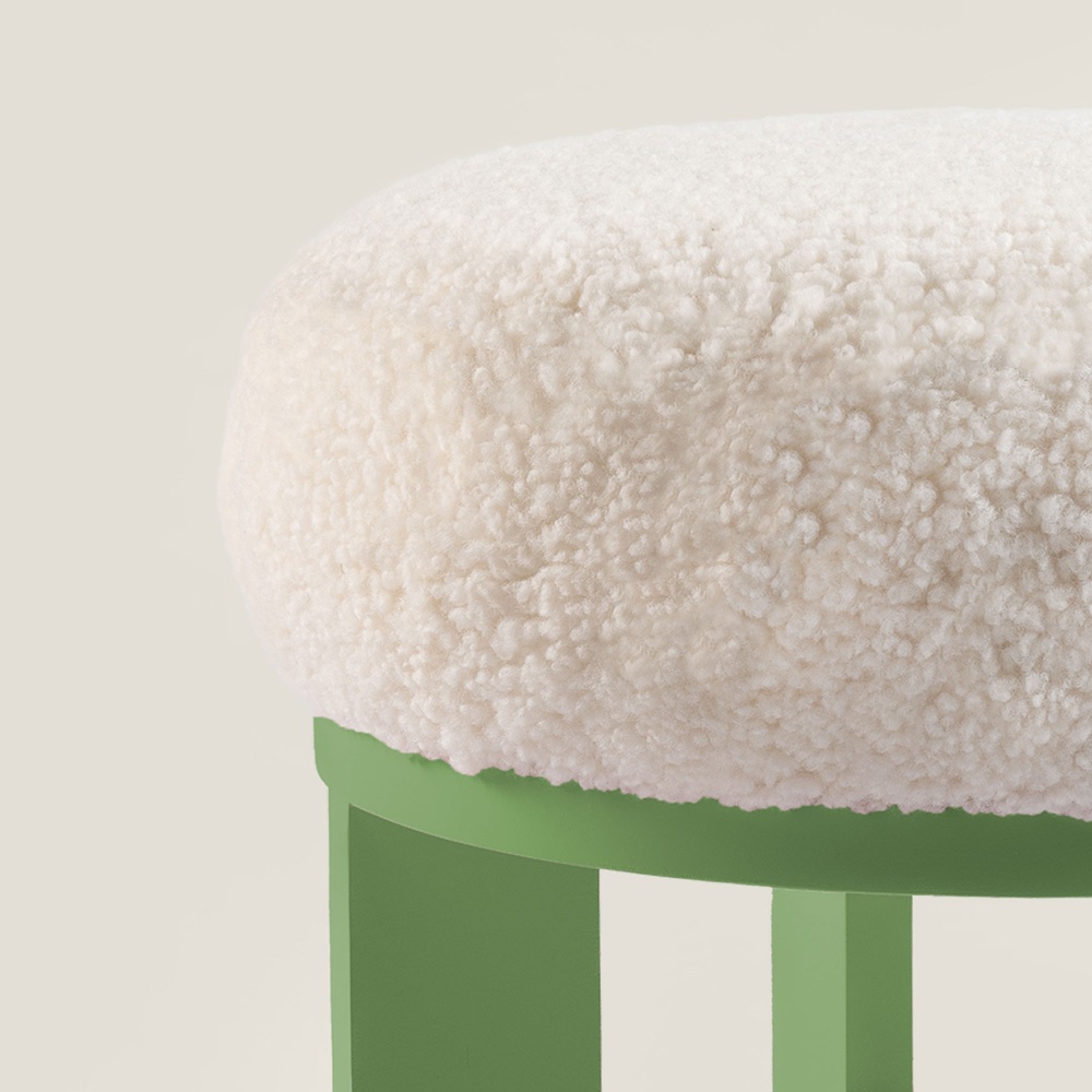 Petit pouf rond en bois laque vert clair avec une assise confortable en mouton blanc