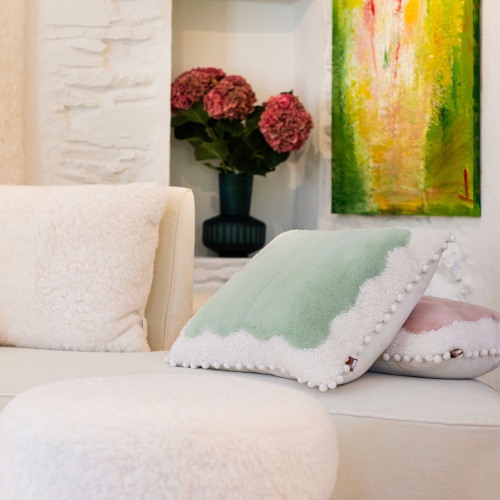 A soft white and green cushion for a cosy setting.