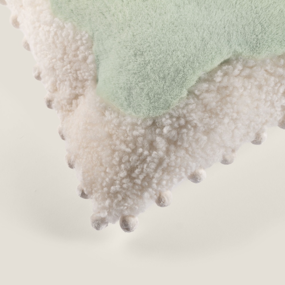 The white silk pompom trimmings make this cushion elegant.