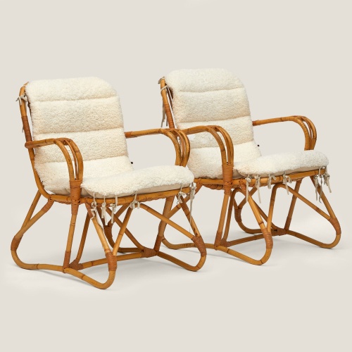 Pair of rattan armchairs with shearling cushions.