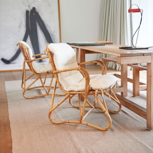 Pair of rattan armchairs with shearling cushions.