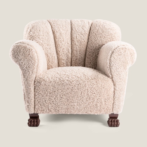 Fauteuil majestueux en peau lainée beige, et pieds en pattes d'animal.