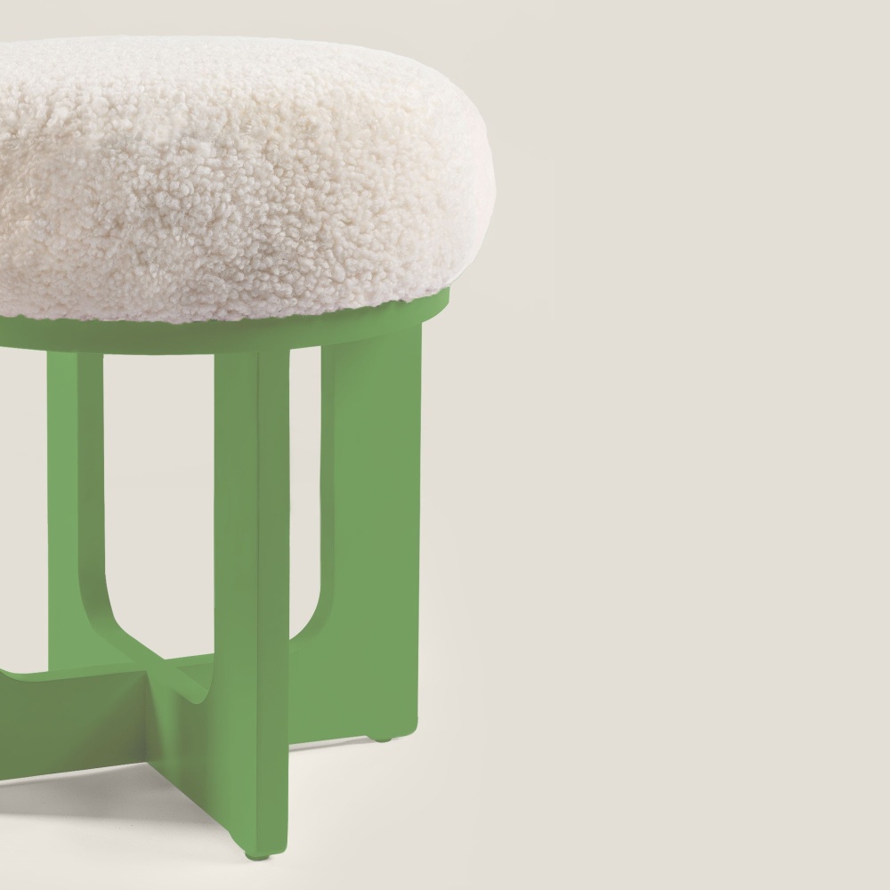 The geometric shape of the legs and the wood contrast with the rounded shape of the curly shearling seat.