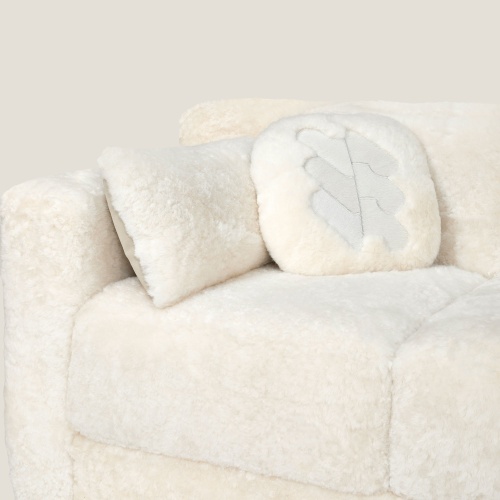 Coussin en peau de mouton naturelle blanche sur canapé blanc style cube.