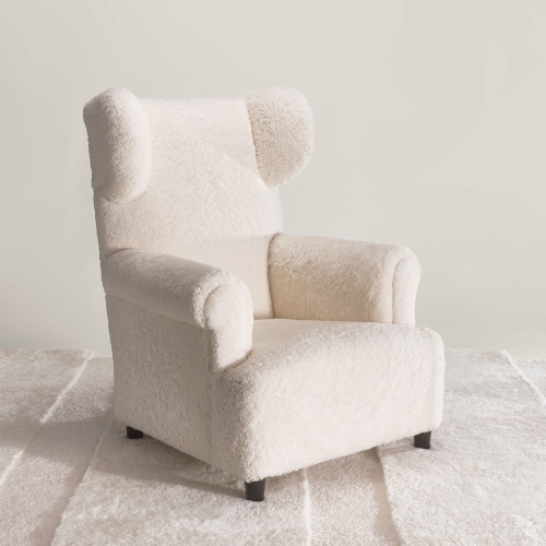 Comfortable wingback reading armchair on custom-made white carpet made in the Norki workshops.