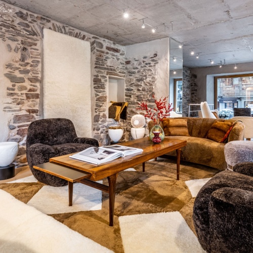 Table basse vintage pour aménager le salon confortable d'un chalet de Megève avec tapis, fauteuils et canapé.