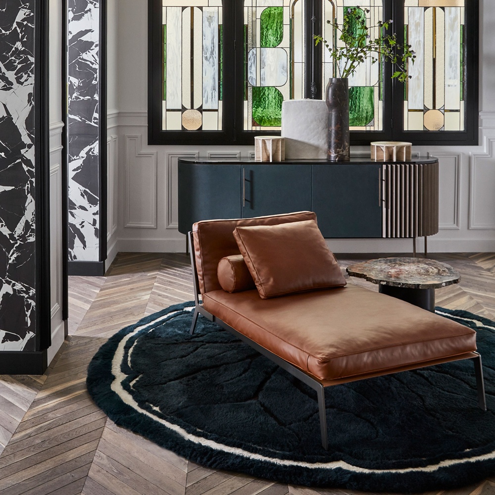 Large green rug and camel leather daybed, in a classic and modern Parisian apartment.