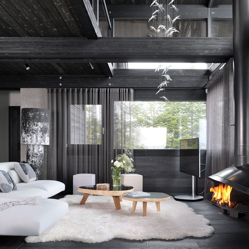 White rug contrasting with the black wooden living room of a contemporary luxury mountain chalet interior design.