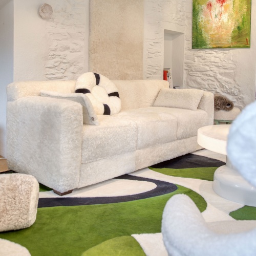 White high-end Montaigne sofa by NORKI matches our green Saint-Peter rug in our Megève showroom in the french Alps.