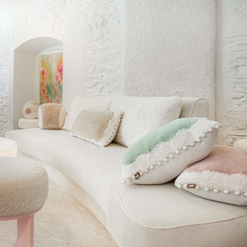 4-seater sofa in velvet and white wool skin, decorated with pastel-colored cushions in haute couture finishes.