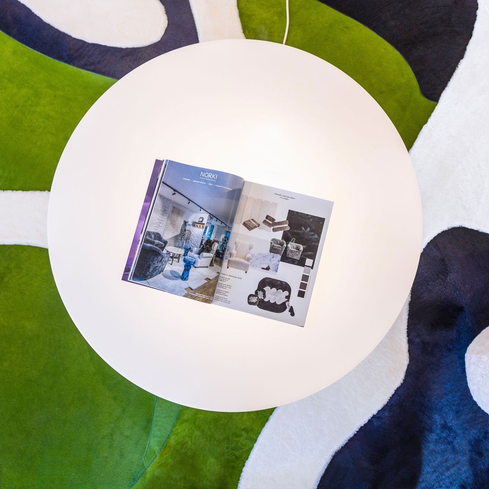 Une décoration moderne dans la boutique Norki de Megève avec un tapis vert,  bleu et blanc et une table basse vintage