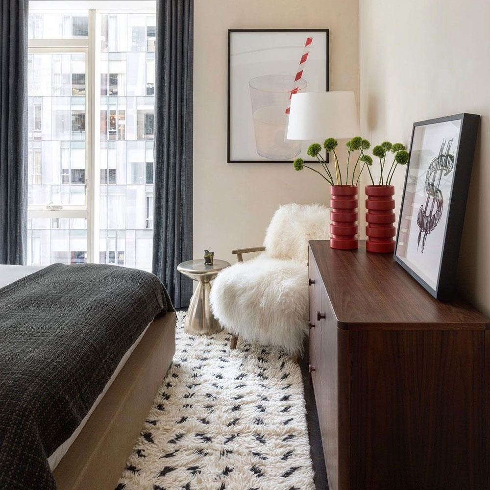 A very elegant decoration with a w designer white armchair and dark wood sideboard in an urban interior.