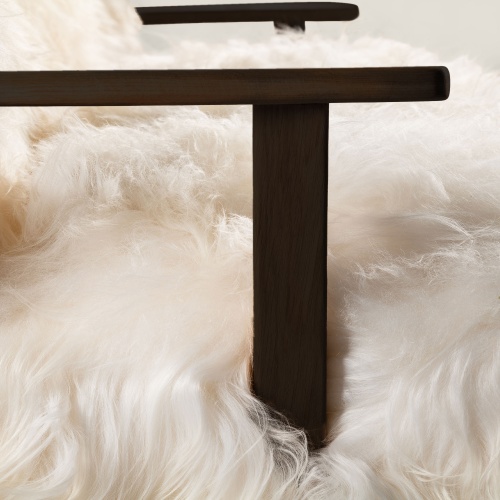 Black-stained solid oak armrests contrast with an attractive seat entirely upholstered in luxurious white sheepskin.