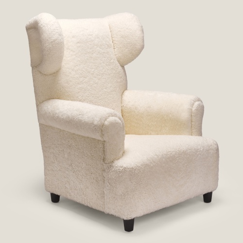 Fauteuil blanc à oreilles de créateur fabriqué en France : un luxueux fauteuil de lecture gainé de peau lainée pour votre salon.