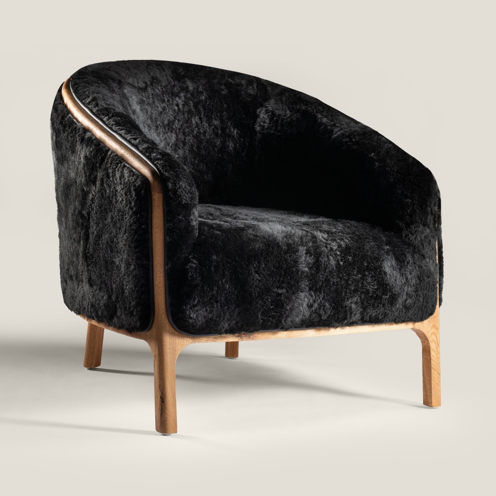 Luxurious, modern, wrap-around NORKI armchair upholstered in black leather or seharling. Ideal for your living room or bedroom.