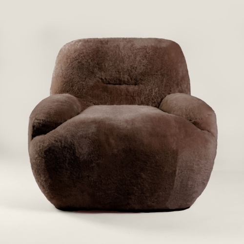 Fauteuil design sur socle pivotant tapissé de peau lainée chocolat dans les ateliers Norki. Un luxueux mobilier made in FRANCE.