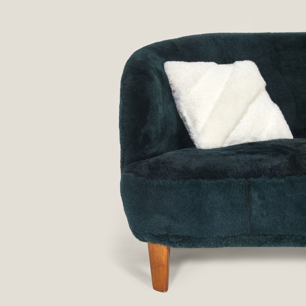 Un coussin blanc raffiné pour décorer un canapé chic vert foncé