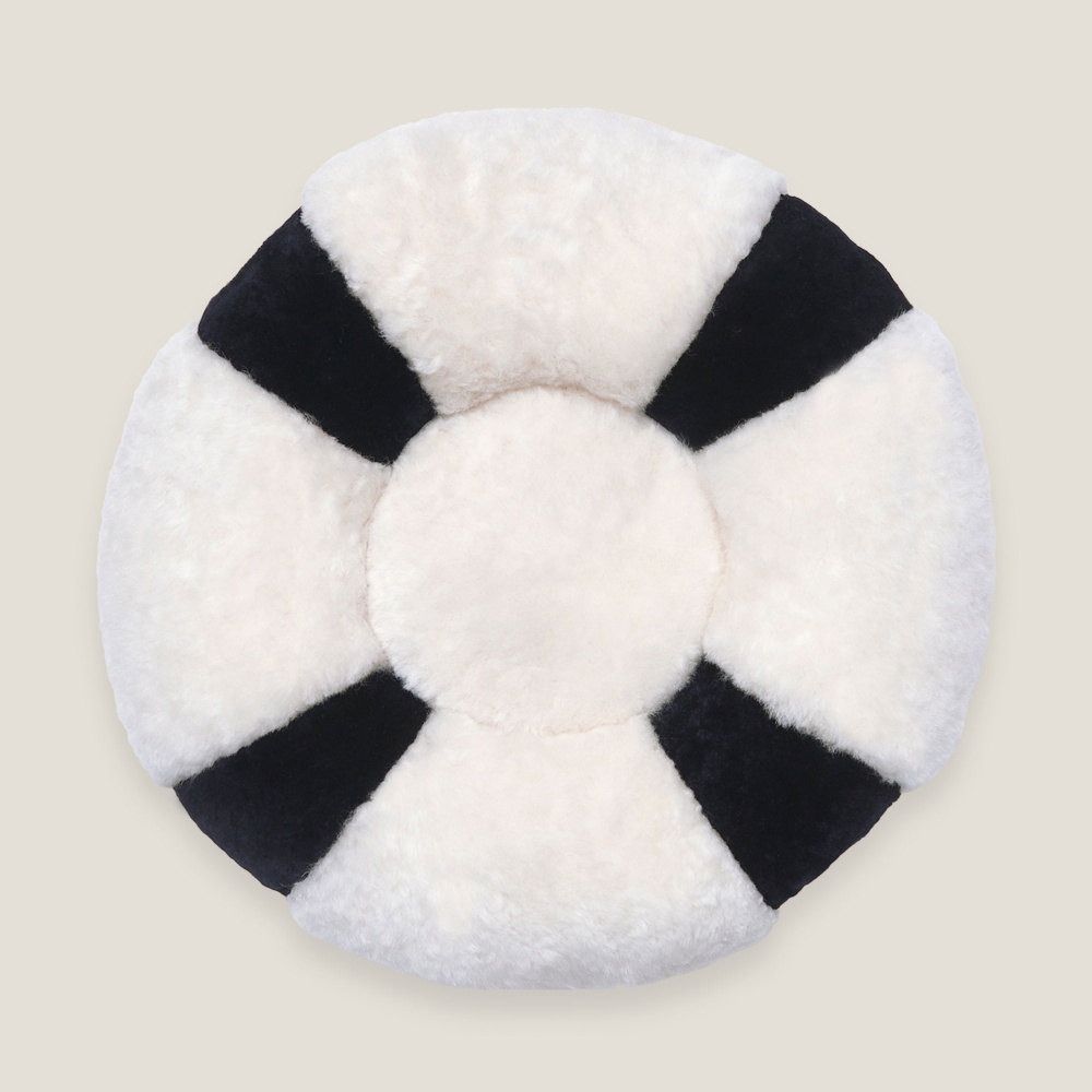 A cushion like a lifebuoy, blue and white. A cushion in natural shearling and sheepskin.