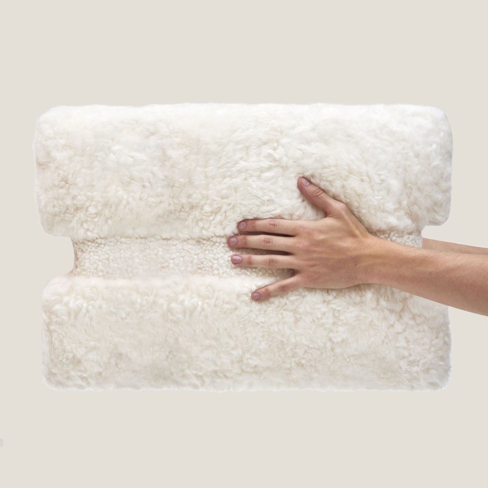 Elegant soft and warm cushion in white sheepskin with neat and luxurious finishes