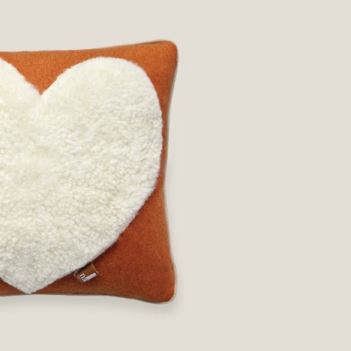 Luxurious square saffron orange cushion with a large heart in white shearling