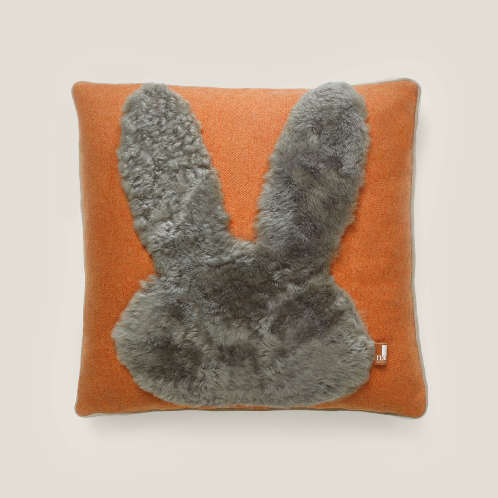 Coussin doux et confortable orange et beige avec une application luxueuse en forme de lapin en peau lainée