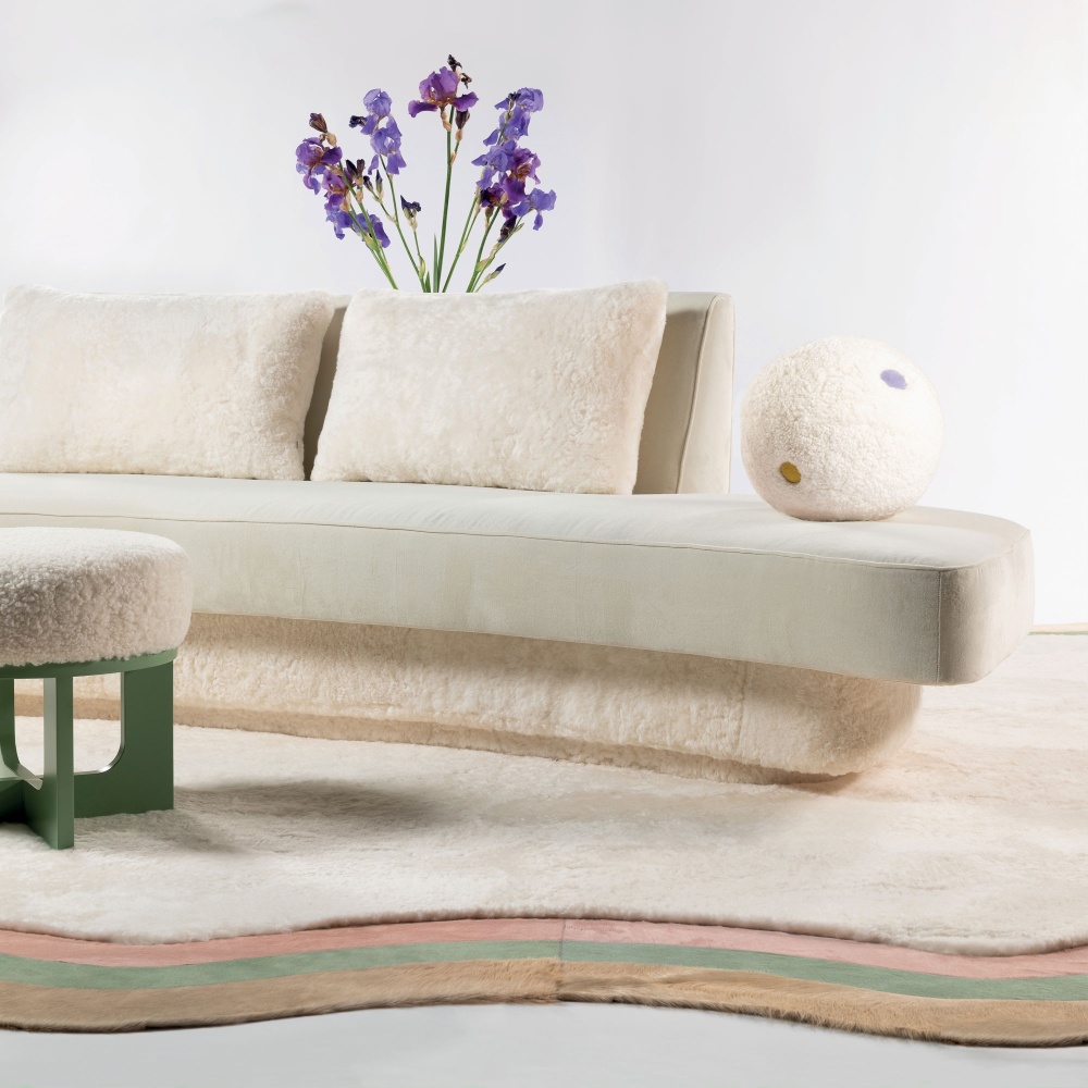 Organically shaped sofa, light green pouf, naive and poetic rug matched with a ball cushion in shearling and leather