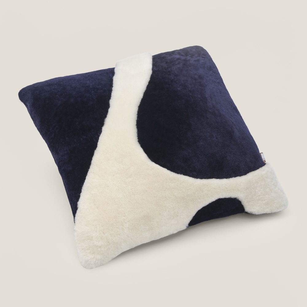 Blue cushion with a white motif that reminds us of sea foam.