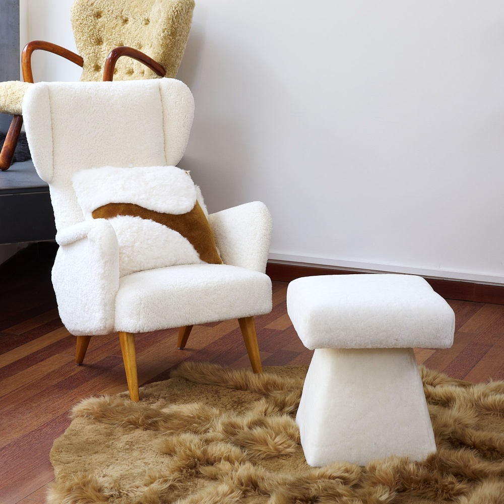 Notre coussin Saint-Peter blanc et camel sur un fauteuil vintage à oreille.