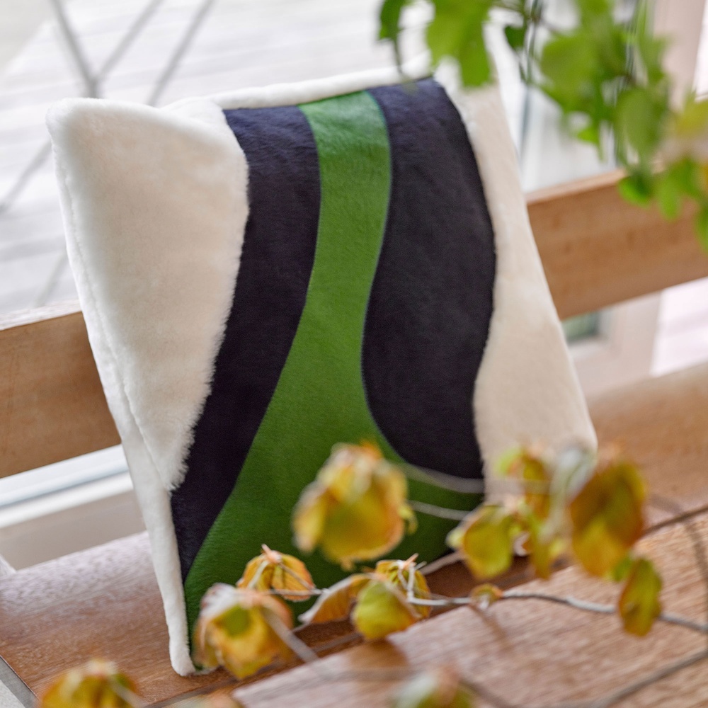 Notre coussin Saint-Peter vert, bleu et blanc sur un banc en bois.