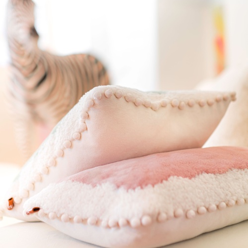 A soft white and pink luxury cushion for a cosy setting.