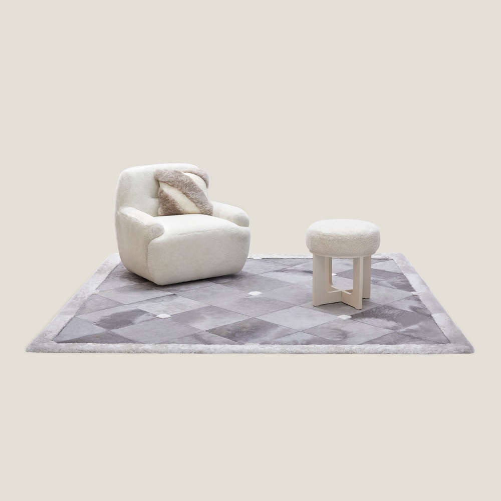 Grand tapis carré blanc haut de gamme dans un décor doux et design avec un pouf, un fauteuil et un coussin signés Norki.