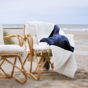 Soft white throw with a navy-blue pattern that reflects the surrounding nature by the sea. Wool lining.