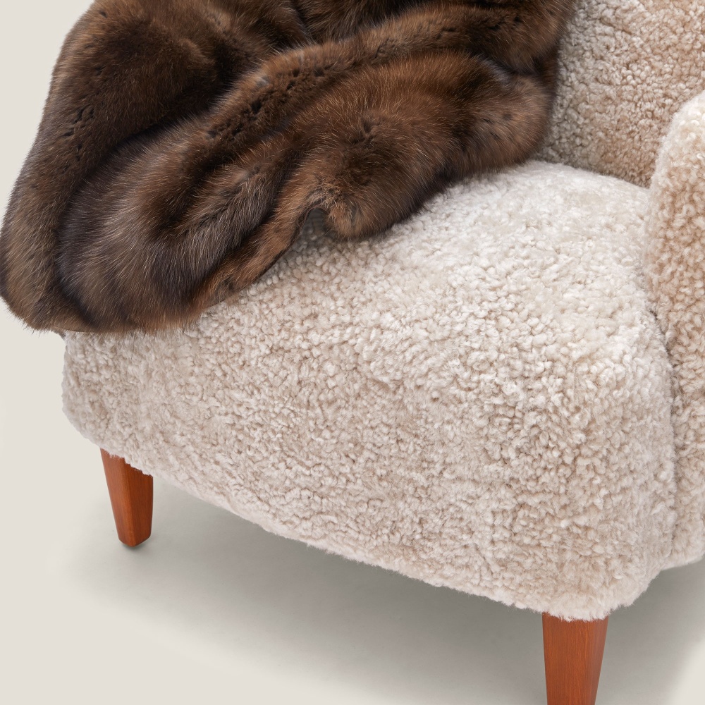 A comfortable, top-of-the-range armchair in curly shearling, with beech legs.