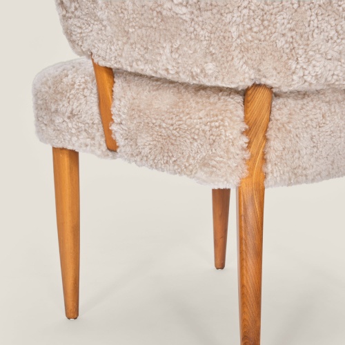 A pair of chairs entirely upholster with beige tinted curly shearling in the Norki workshop.