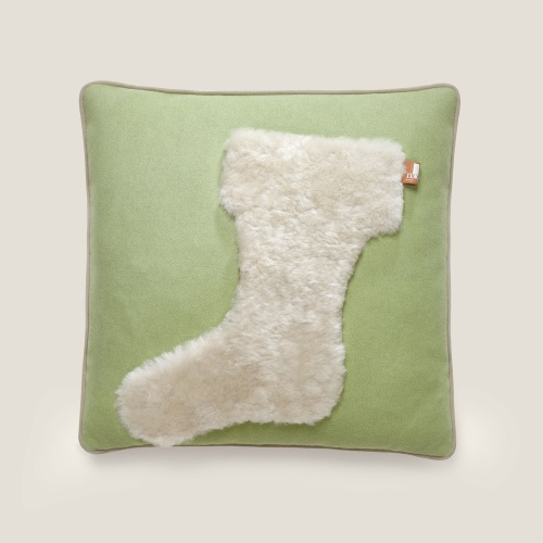 Coussin haut de gamme, vert avec un motif de botte beige en mouton, vu de face.