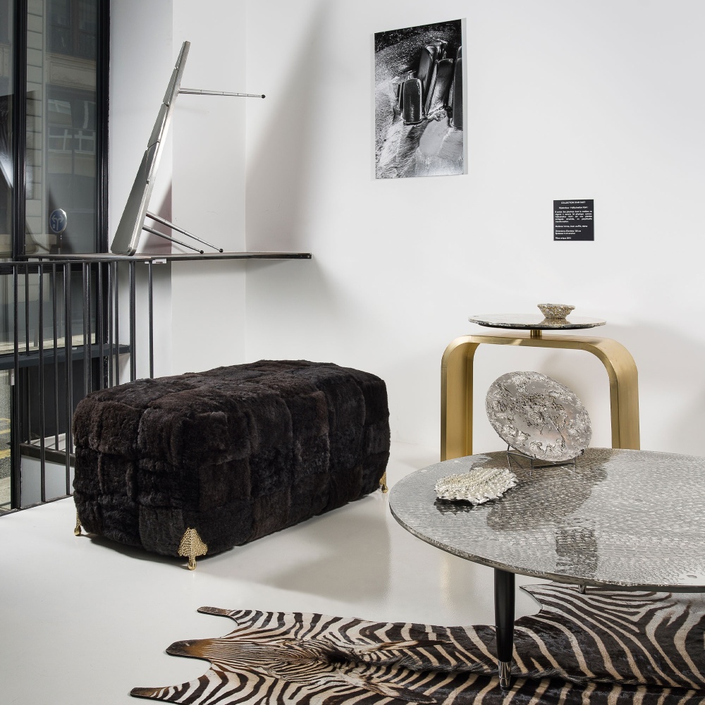 A large black stool in sheared natural sheepskin with brass legs for a modern, elegant look.