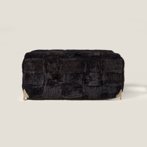 Vue de face du grand pouf noir en mouton naturel, un pouf signé Norki, haute couture.