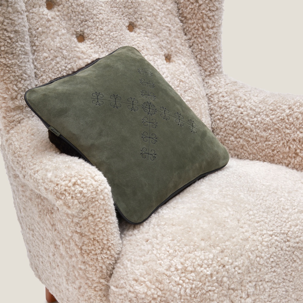 Small khaki cushion embroidered on a vintage armchair in white wool.