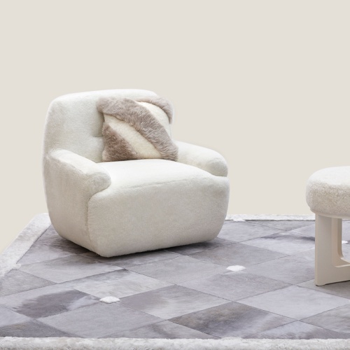 A small, comfortable white armchair on a custom-made grey wool rug, designed by Norki.