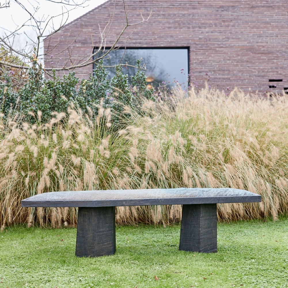 Un banc de designer en chêne massif et en peau de vache bleu/vert pour une décoration d’intérieur brutaliste et simpliste.