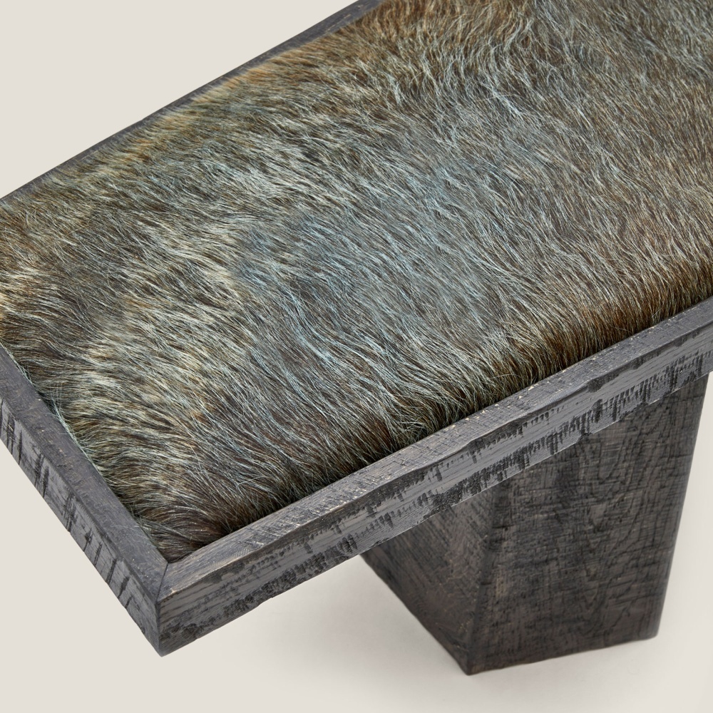 A blue/green-tinted cowhide that blends perfectly with the stained solid wood of this designer bench.