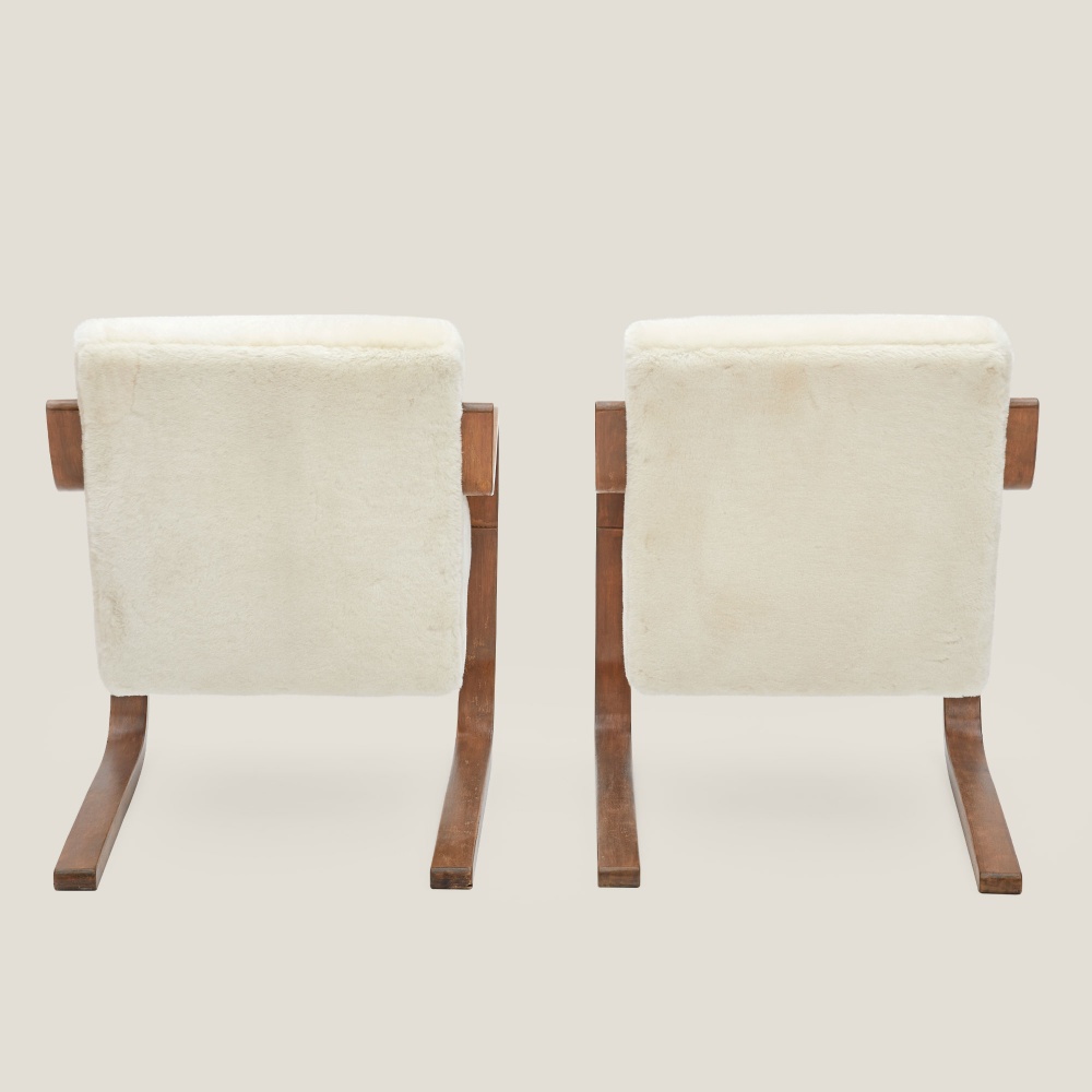 Back view of a pair of designer armchairs by Alvar Aalto, in birch and upholstered in velvet shearling.