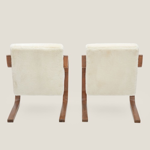 Back view of a pair of designer armchairs by Alvar Aalto, in birch and upholstered in velvet shearling.